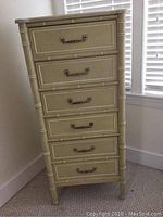 Front view of 5 drawer lingerie chest with decorative rectangular drawer fronts and metal handles, placed in a corner next to window.