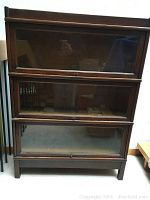 Full front view of three-tier bookcase showing stacking sections and glass doors