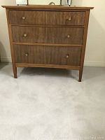 Front view of the dresser showing three drawers and brass knobs