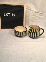 Photo showing small bowl and pitcher side by side under consistent lighting with neutral cloth background and LOT 14 sign