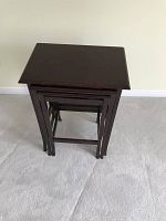 Set of three dark wood nesting tables stacked together