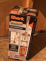 Vacuum box showing brand Shark Rocket Professional claims including better cleaning and lighter weight than Dyson DC42, with anti-allergen seal and enhanced swivel features.