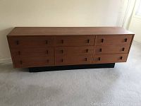 Front view of entire dresser showing nine drawers and black plinth base