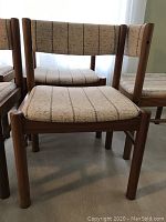 Front view of one teak dining chair showing seat, backrest, and frame