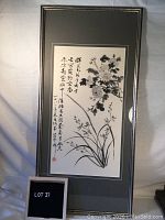 Full view of framed Asian brush art with calligraphy and floral imagery on paper, showing the entire framed piece including the frame and matting.
