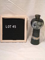 Full view of vase next to sign for scale