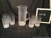 Full set: one pitcher and six glasses arranged on black backdrop