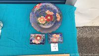 Full set of three pieces on blue cloth backdrop; one large round plate with two smaller rectangular dishes.