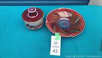 Glazed purple-red and white porcelain garlic pot with cover, and circular vibrant red porcelain dish with crimped rim.