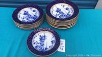 Stack of 23 Royal Doulton Kew plates showing cobalt blue and gold gilt borders and blue botanical center design