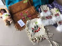 Overview of lot showing doll, two handbags, and gloves with fur trim and tassels.