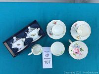 Assortment of fine china items including 4 tea cups, 4 saucers, creamer, sugar bowl, and boxed salt and pepper shakers