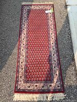 Full view of the rectangular red area rug showing the overall pattern and fringed ends.