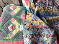 Two vintage quilts displayed folded and partially layered to show front designs and colors.