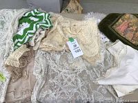Pile of vintage lace cloths including various sizes and patterns in white and cream color with tags visible.