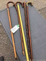 All four wooden canes displayed on a surface with measuring tape showing approximate length of 33 inches.