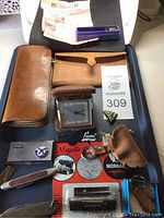 Full view of lot including Birks clock, wallet, pencil case, knives, stamp case, and other accessories on a tray.