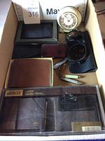 View of the lot in a box showing wallets, clock, pocket knives, and sunglasses including Amity leather billfold in box