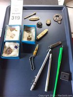 Tray view showing brooches, badge, pins and toothpick holder next to lot card