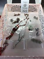 Vintage jewelry lot arranged in tray including necklaces, earrings, and brooches