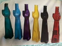 Photo of six empty colored glass wine bottles shaped like stylized female torsos in different colors