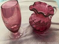 Pink art glass vase and matching pitcher set shown on white fabric background