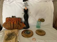 Overview of the lot with the vintage purse, black mannequin jewelry holder, perfume bottle, metal deer head decoration, two compact cases, and a ring.