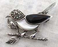 Front view of the bird brooch showing mother of pearl, black onyx inlays, marcasite stones on head and tail, and detailed leaves on the branch.
