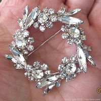Front close-up of Sherman brooch showing clear round and marquise Swarovski crystals in a circular wreath pattern on rhodium plated base.