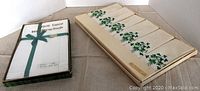 Two boxes of Irish linen items: box on left contains white handkerchiefs tied with green ribbon, box on right contains cream-colored napkins with green clover leaf embroidery.
