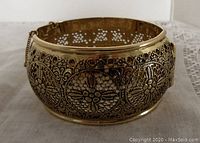 Front angle view of vintage Whiting Davis bangle showing detailed open work floral pattern and safety chain.