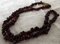 Full view of the garnet chip necklace laid out on white cloth showing the bead chips and clasp detail.