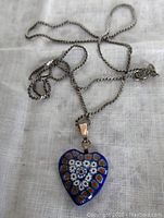 Photo showing the full chain and pendant on a fabric background.