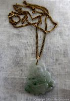 Front view of the jade Buddha pendant hanging on the gold filled flat curb chain, showing the pendant's detailed carving and chain style.
