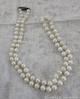 Full view of the vintage Akoya cultured pearl necklace laid out on fabric showing length, pearl size, and color tone.