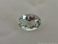 Top view of the oval cut Brazilian green amethyst loose gemstone showing its faceted surface and light green color.