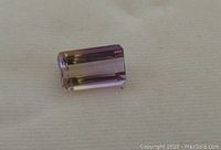 Close-up photo of octagonal emerald cut loose ametrine gemstone showing purple and yellow hues.