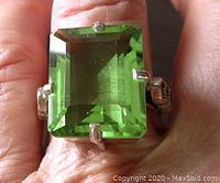 Close-up photo of the ring on a finger showing the large emerald cut green quartz stone with prong setting.