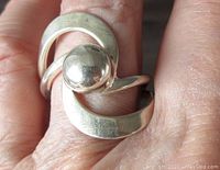 Ring worn on finger showing the half ball centerpiece and modernist design.
