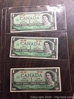 Front sides of three uncirculated Canadian Centennial one dollar bills featuring Queen Elizabeth II.