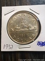 Reverse of the 1937 Canadian silver dollar coin showing canoe with two voyageurs and inscriptions.