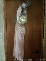 Full view of life-size skeleton Halloween decoration hanging with glowing green eyes lit up