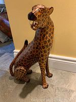 Front and side angled view of large hardwood cheetah figurine showing detailed painting of spots, face, and body posture while sitting.