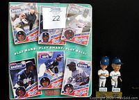 Front view of Dodgers binder notebook with player card reproductions and two bobbleheads