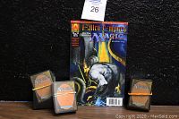 Comic book standing between three rubber-banded stacks of Magic: The Gathering cards on table