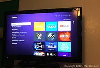 Front view of TV screen showing Roku interface with menu options and streaming channel icons.