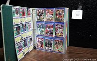 Open binder image showing football trading cards in clear sleeves with front/back sides visible.