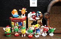 M&M's collectibles arranged on a black background including figurines, photo booth tin, decorative chimney figurine.