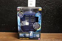 Front view of the boxed Doctor Who TARDIS showing the Police Public Call Box design, branding, and features text about flashing lantern and sound effects.