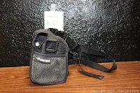 Black adjustable carrying case with shoulder strap and mesh side pocket, labeled Polaroid.